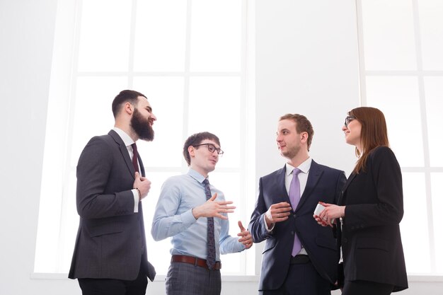 Employees meeting with the boss. Corporate, success, brainstorming. Teamwork concept. Business people in light white office interior with windows, copy space