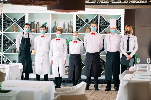 Employees of a Restaurant or Hotel in protective masks. End Of Quarantine. Restaurant Manager and his staff on the terrace. interaction with the chef in the restaurant.