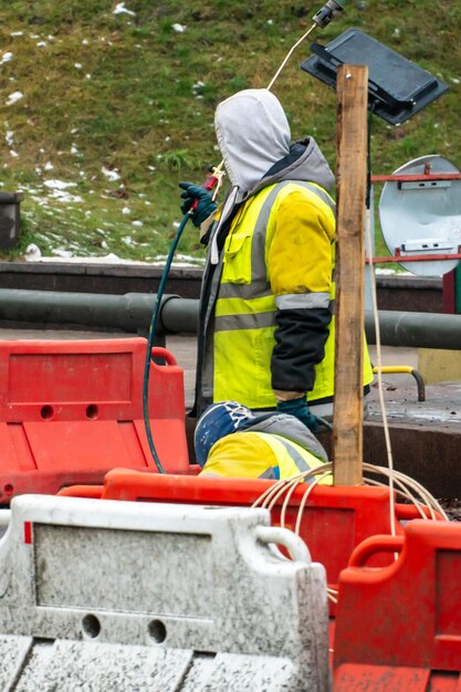 Photo employees of the road service in special yellow vests perform work on the repair of the roadway restoration of the deformation seam of the automobile bridge