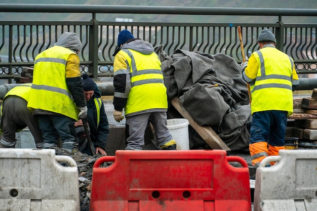 Employees of the road service in special yellow vests perform work on the repair of the roadway Restoration of the deformation seam of the automobile bridge