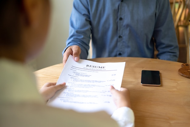 写真 雇用者は、彼の履歴書を読んでテーブルに座っている若い男性求職者にインタビュー