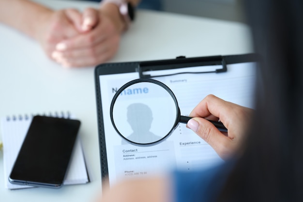 Employer looking at application form with magnifying glass closeup