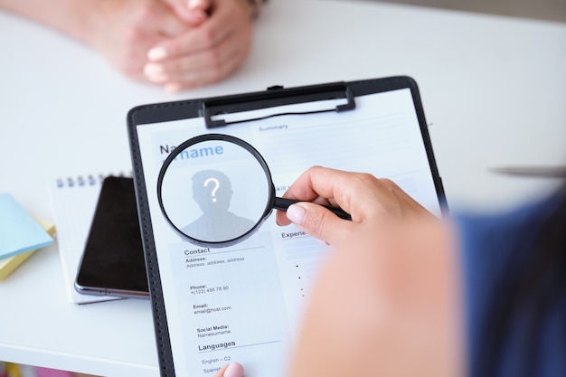 Photo employer looking at worker resume with magnifying glass closeup