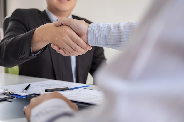 Employer in suit and new employee shaking hands after negotiation and interview placement