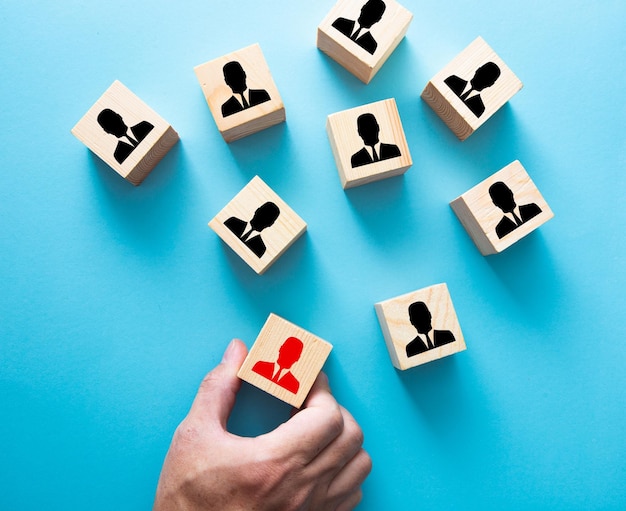 Employment choice concept Hand choosing a wooden person block from a set