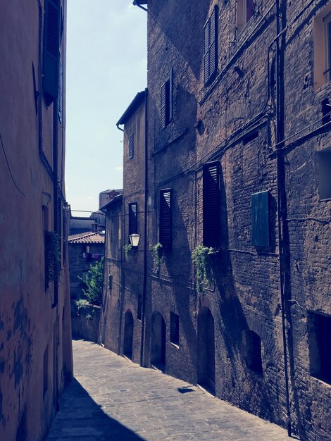 Empty alley amidst buildings against sky in city