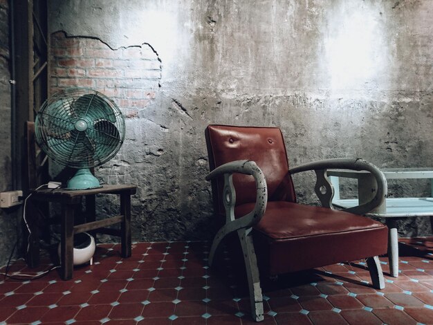 empty armchair by electric fan in old room