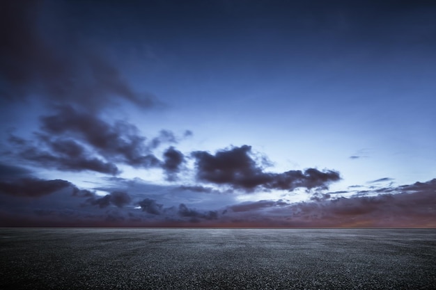 Empty asphalt floor with dramatic sunset sky .