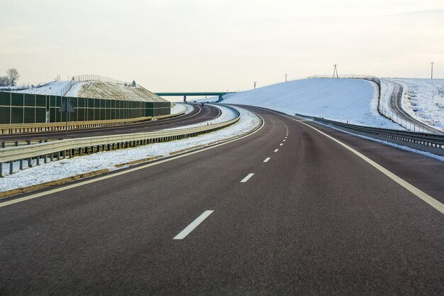 Empty asphalt highway stretching to horizon under high bridge.