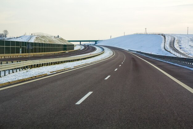 高い橋の下の地平線に伸びる空のアスファルト道路。