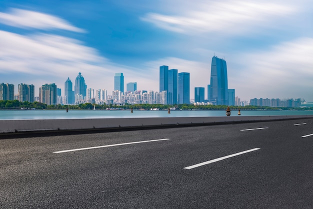 The empty asphalt road is built along modern commercial buildings in China's cities.