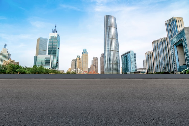 The empty asphalt road is built along modern commercial buildings in China's cities.