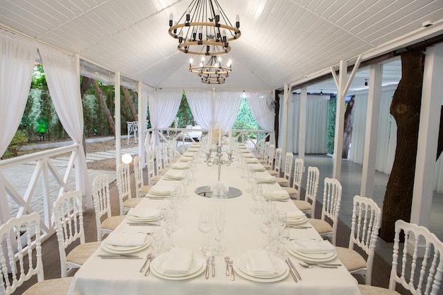 Empty banquet hall ready to receive guests on the summer terrace. white festive table