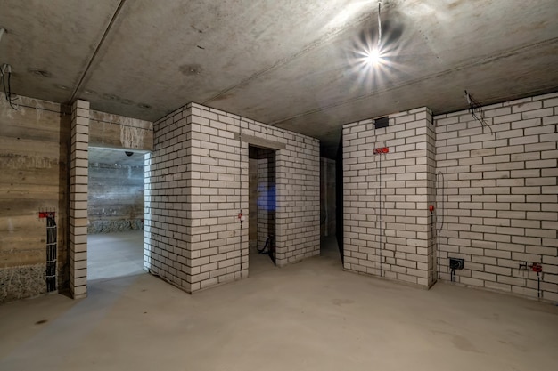 Photo empty basement room with minimal preparatory repairs interior with white brick walls