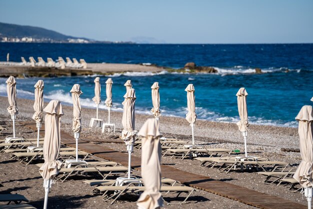 Sedie da spiaggia vuote e ombrelloni chiusi sulla spiaggia in grecia