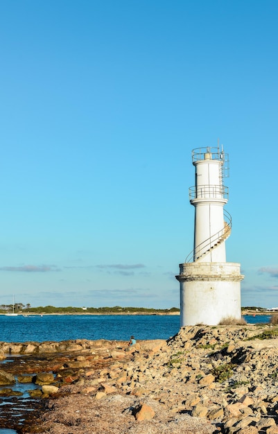 Empty beach of tourists and high lighthouse on formentera island