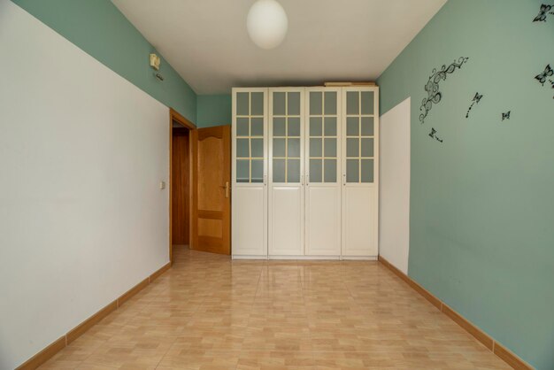 Photo empty bedroom with woodlike stoneware floors green and white painted walls and a fourdoor wood and glass wardrobe