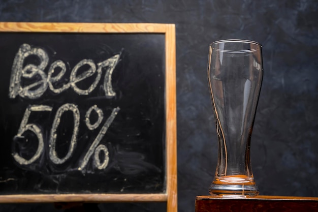 An empty beer glass on a wooden table on a dark background