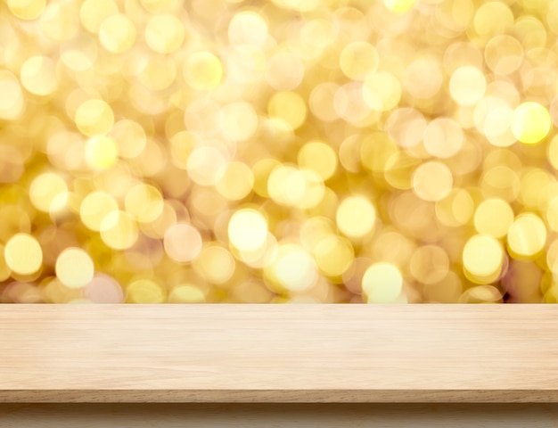 Svuoti il ​​piano d'appoggio di legno beige con la luce astratta del bokeh dell'oro del fondo