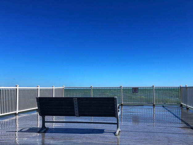 Empty bench against clear blue sky