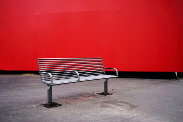 写真 赤い壁に立つ空のベンチ