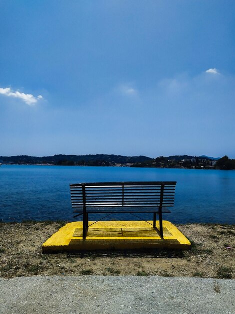 Foto panchina vuota vicino al lago contro il cielo blu