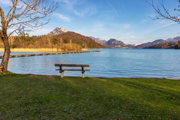 Empty bench by lake against sky