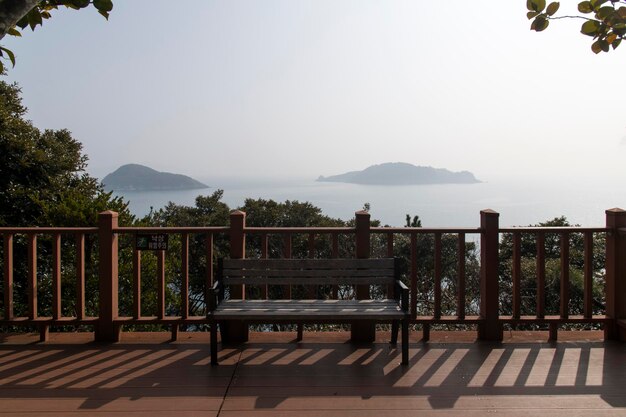 Empty bench by railing against sky