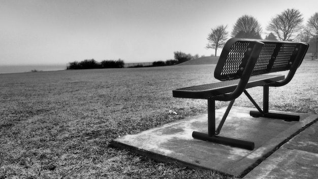 Photo empty bench on field against clear sky