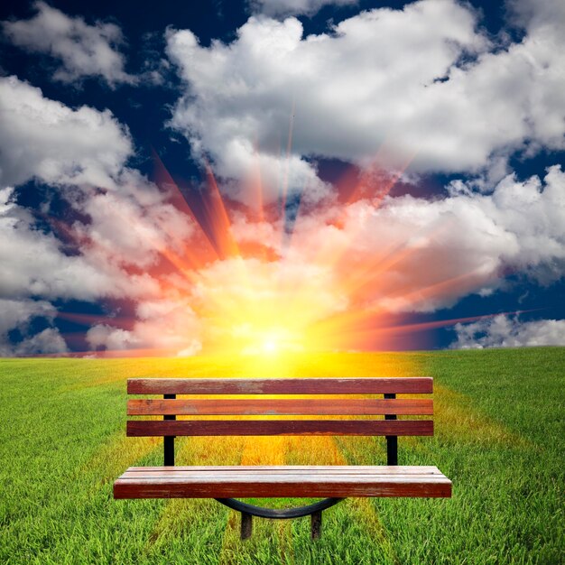 Empty bench on field against sky during sunset