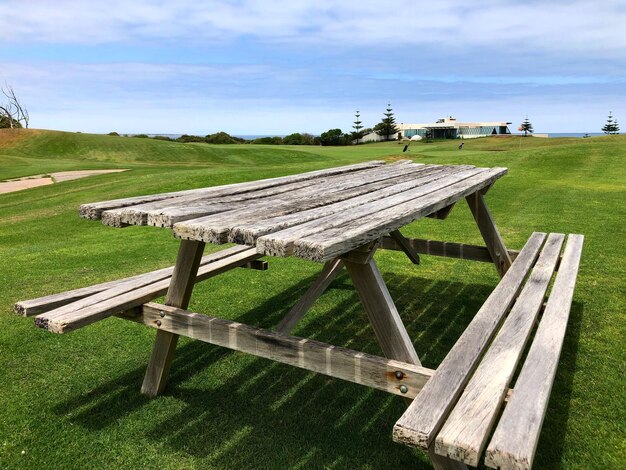 Empty bench on field against sky