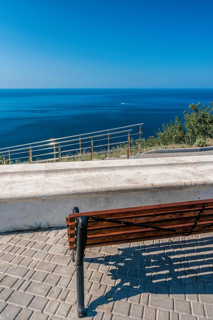 Empty bench on sea shore in a park sea view from mountain travel relax or loneliness concept wooden