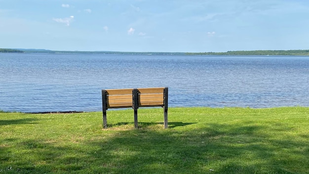 Empty bench on shore by sea against sky