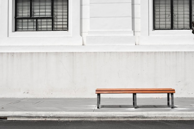 Empty bench on sidewalk against building