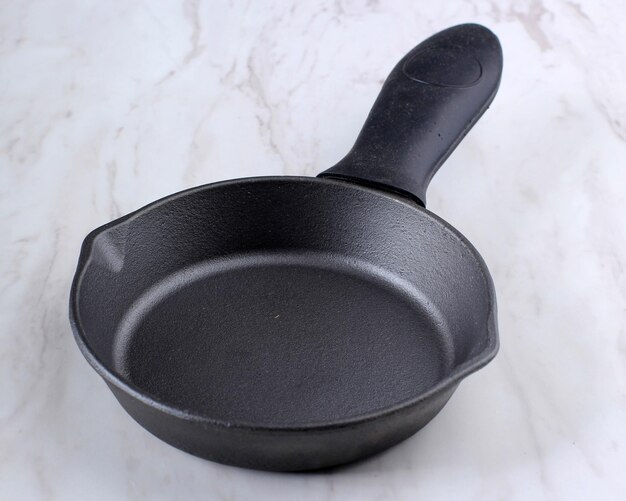 Empty Black Cast Iron Skillet on White marble Background Isolated