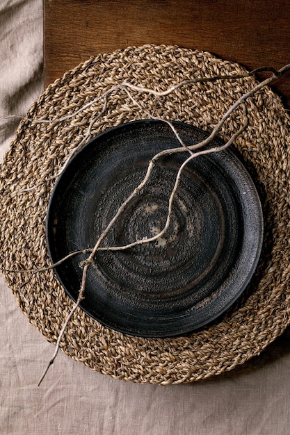 Empty black ceramic plate with dry branch