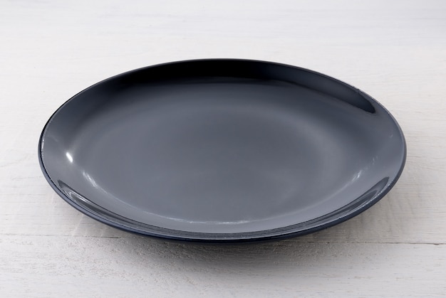 Empty black ceramic plate on wooden table