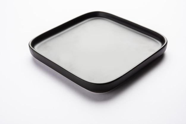 Empty black ceramic square plate isolated on white surface