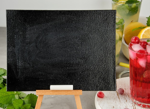 Empty black chalk board for writing a summer drink recipe and a glass with berry lemonade