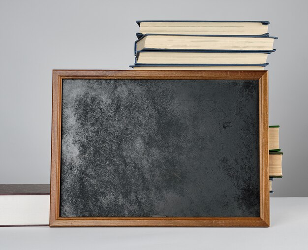 Empty black chalk drawing frame and stack of books