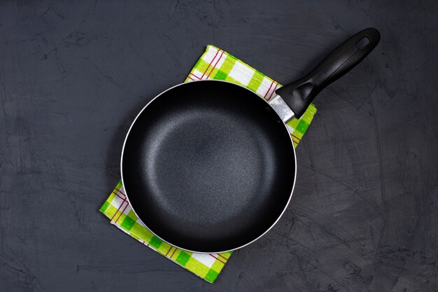 Empty black frying pan with green kitchen towel