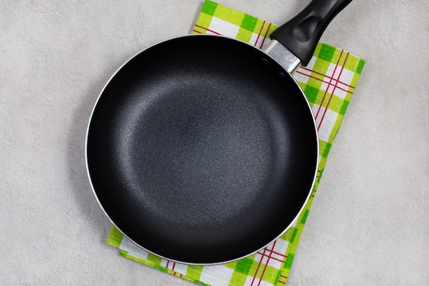 Empty black frying pan with green kitchen towel