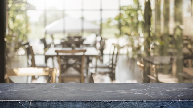 Photo empty black marble stone table top and blurred coffee shop, cafe and restaurant interior background - can used for display or montage your products.