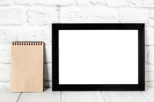 Empty black photo frame on wooden shelf or table. Mockup with copy space