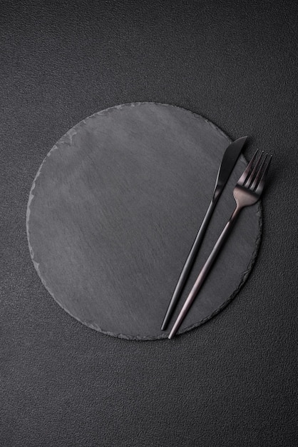 Пустая черная тарелка на темном каменном фоне с копией пространства. Вид сверху