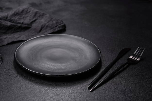 Empty black plate over dark stone background with free space Top view