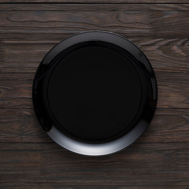 Empty black plate on a wooden table, top view