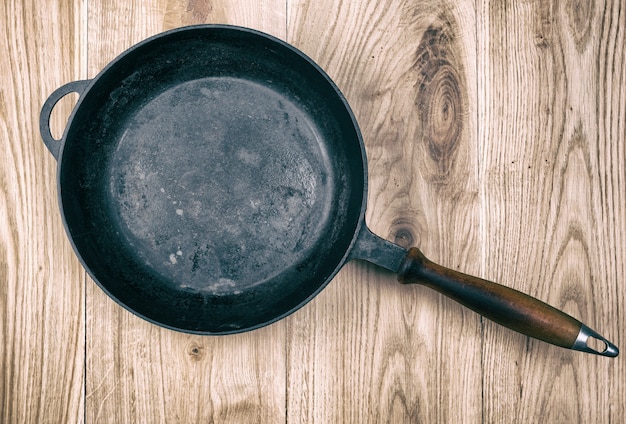 Empty black round frying pan with wooden handle