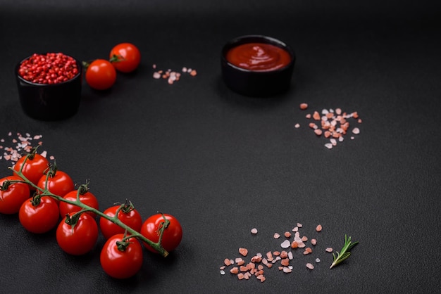 Empty black texture table cherry tomatoes on a twig spices salt and herbs