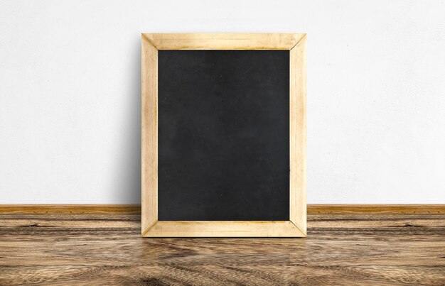 Empty Blackboard leaning at rustic wooden floor and white wall